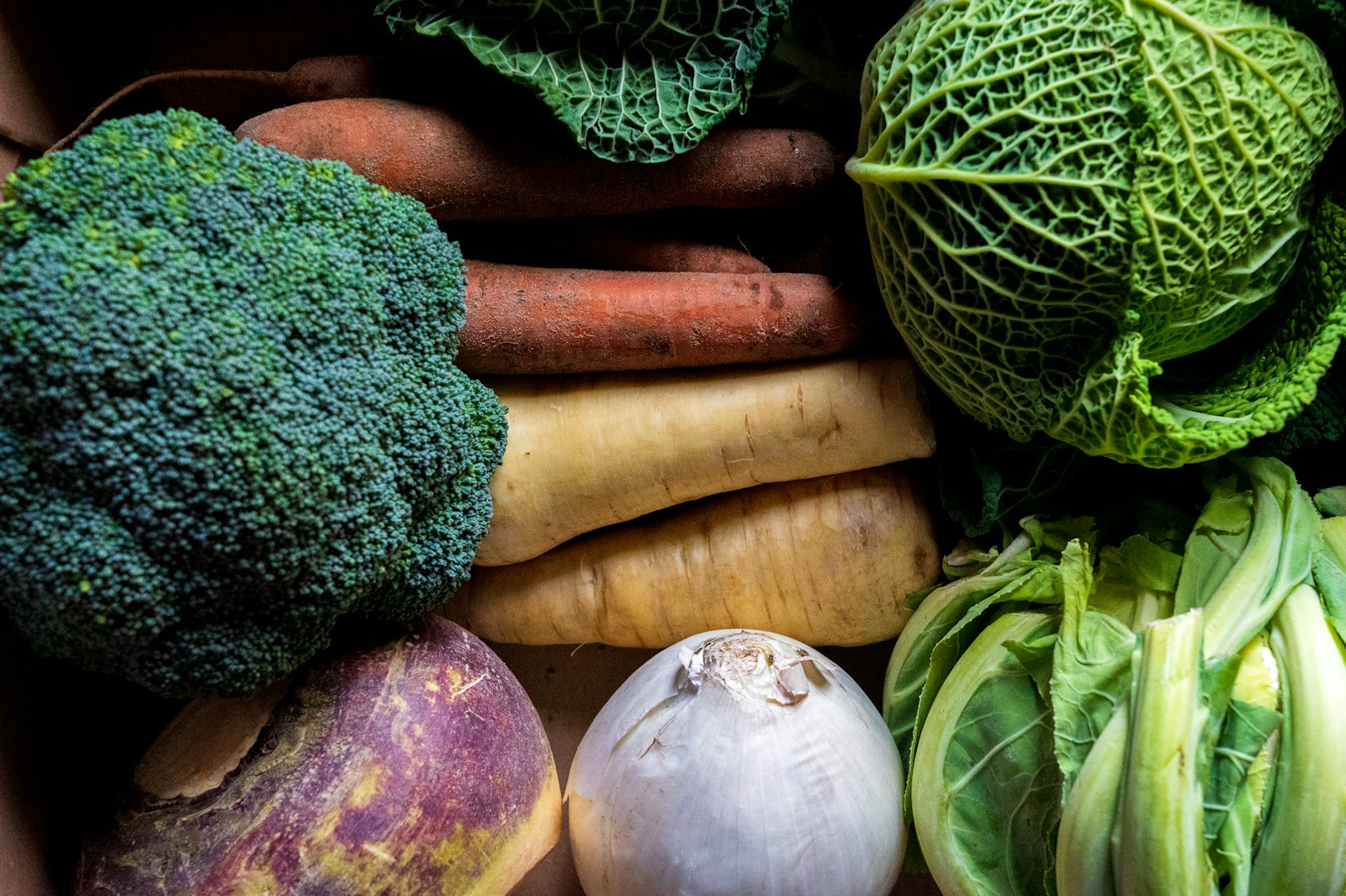 A purple-topped swede beside onion, parsnips, carrots, broccoli and savoy cabbage