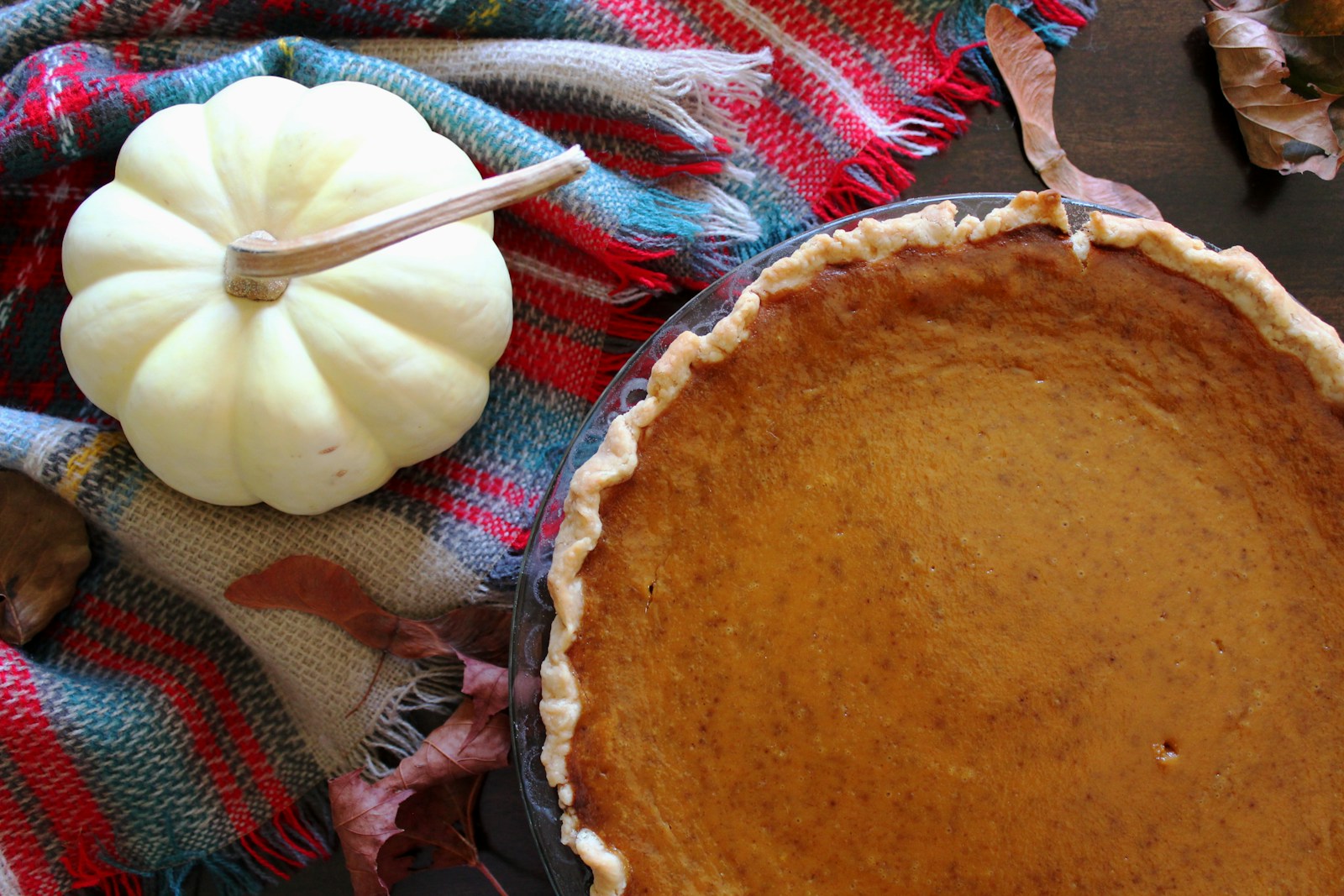 Baked pumpkin pie beside a small white pumpkin, seen from above