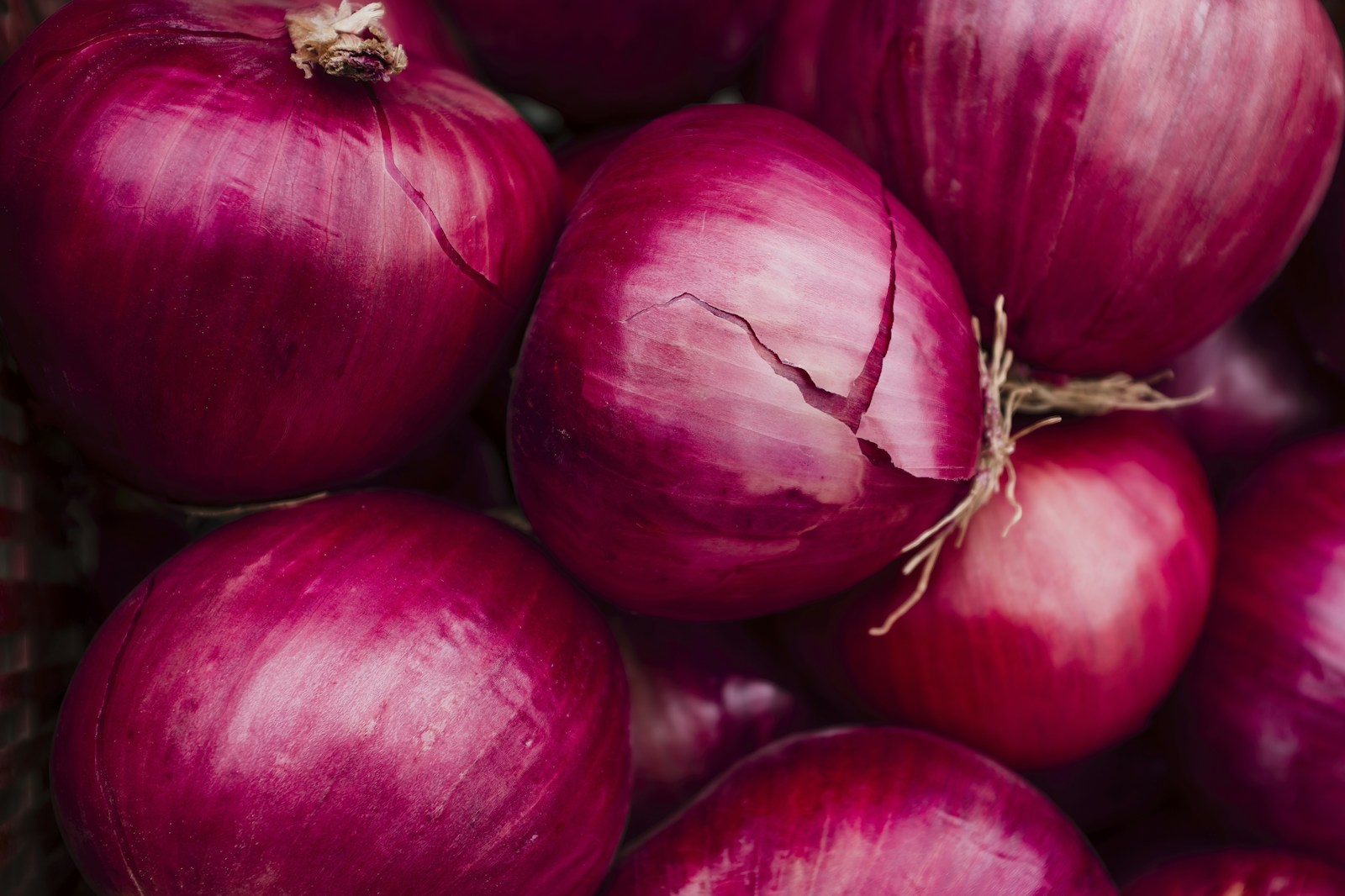 Red onion bulbs with glossy deep purple skins piled together