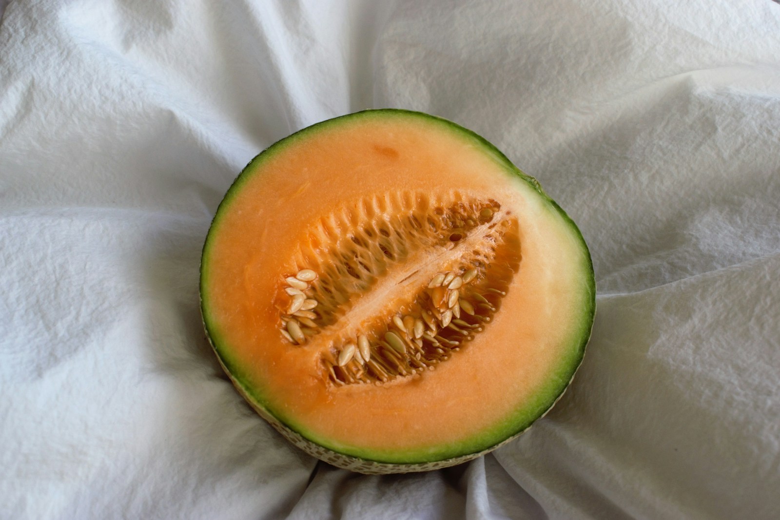 Halved cantaloupe with bright orange flesh and a central cavity of seeds