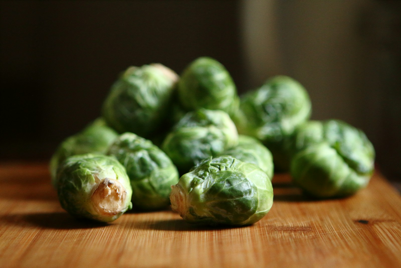 A small pile of picked Brussels sprouts on a wooden board