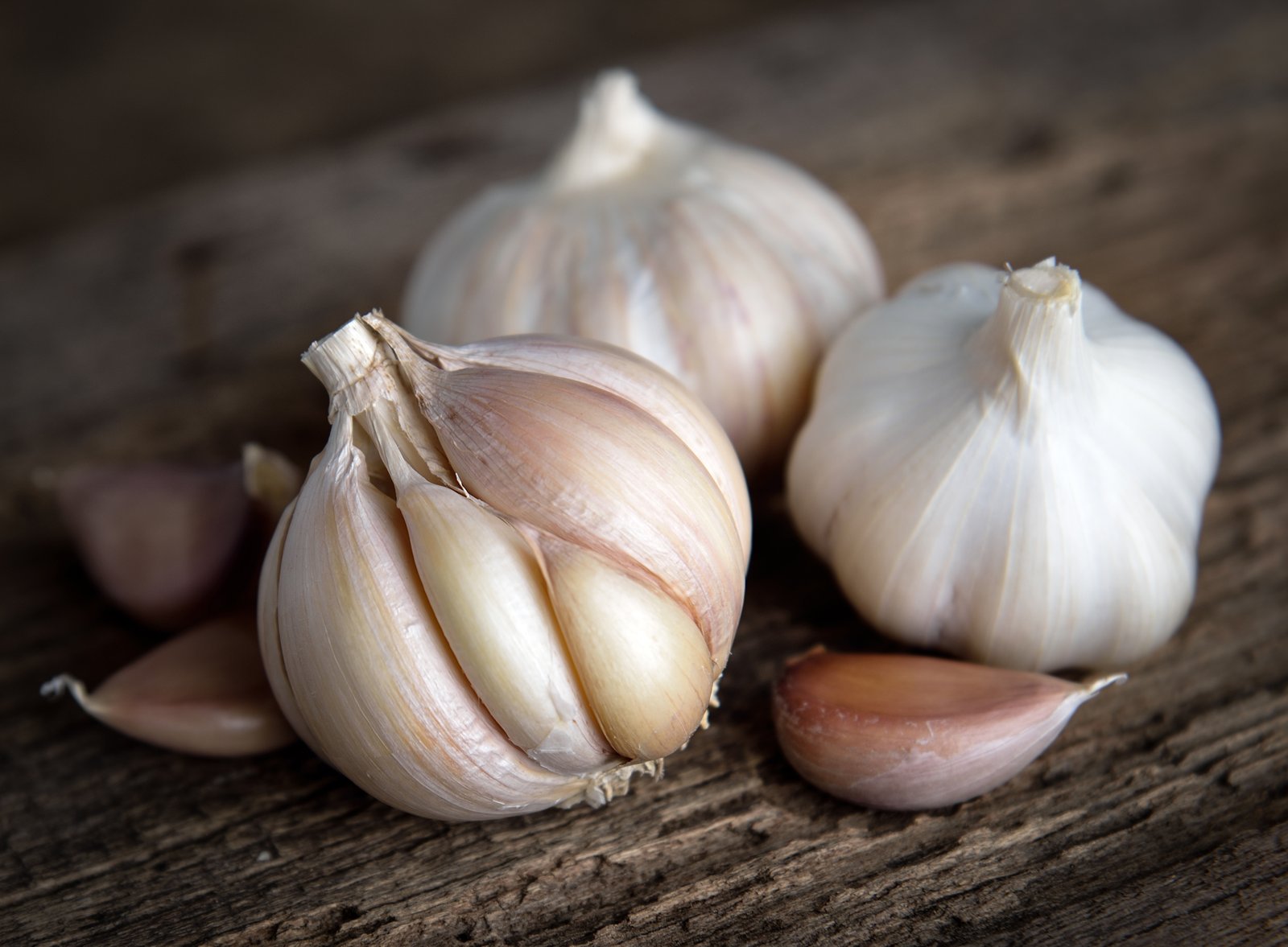 Garlic bulbs and loose cloves with papery skins on a wooden table