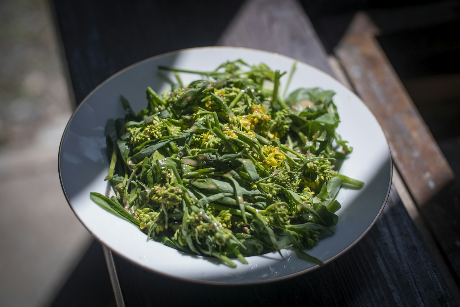 Plate of dressed mustard green shoots and watercress with yellow buds