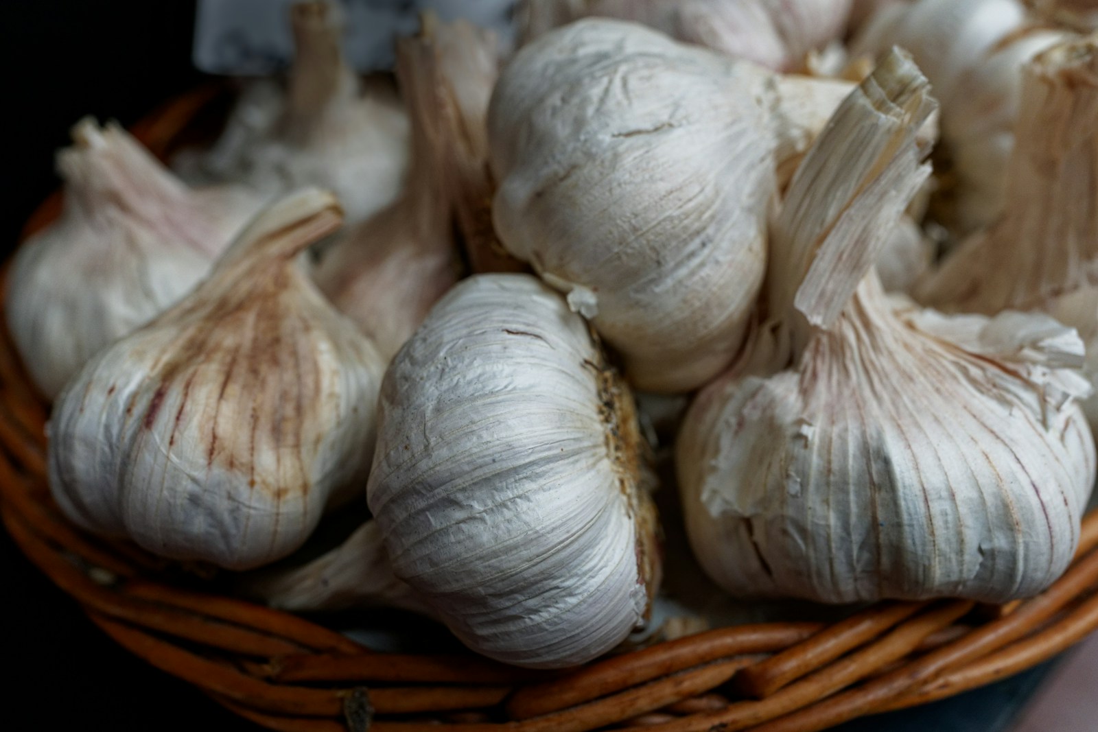 Cured garlic bulbs with papery white skins in a wicker basket