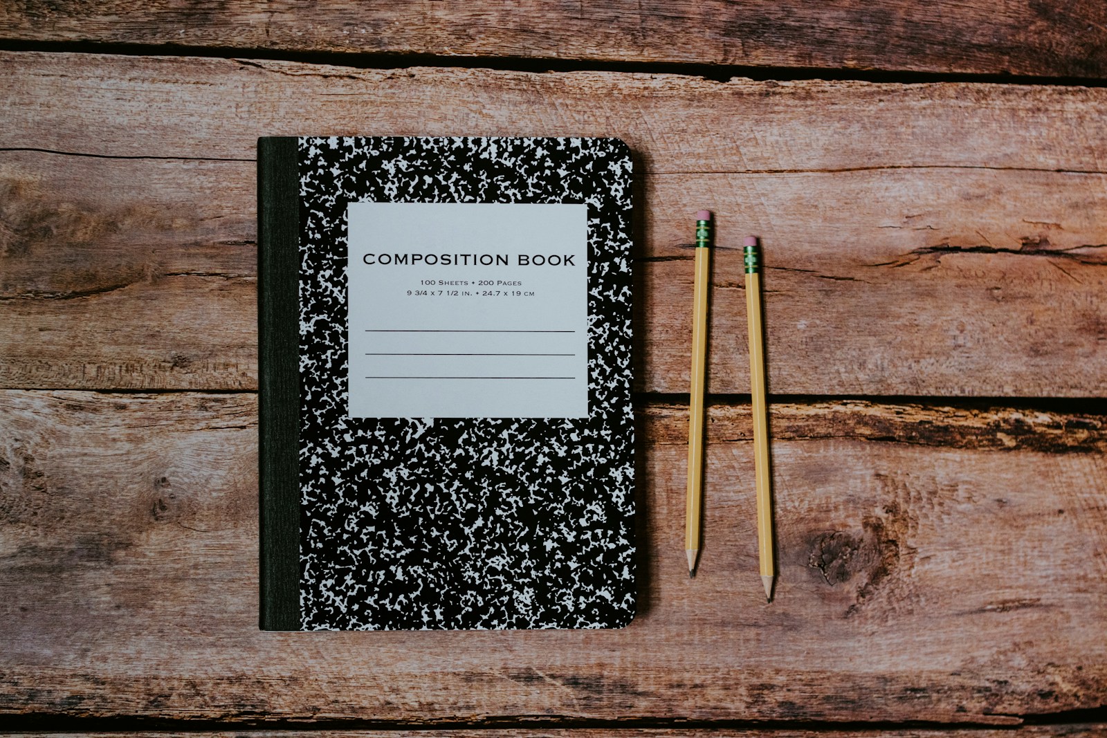 Composition notebook and two pencils on weathered wooden boards
