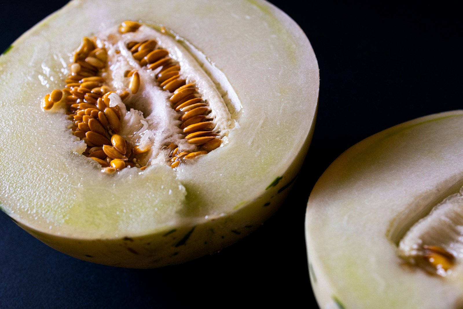 Close view of a halved honeydew melon with pale flesh and golden seeds