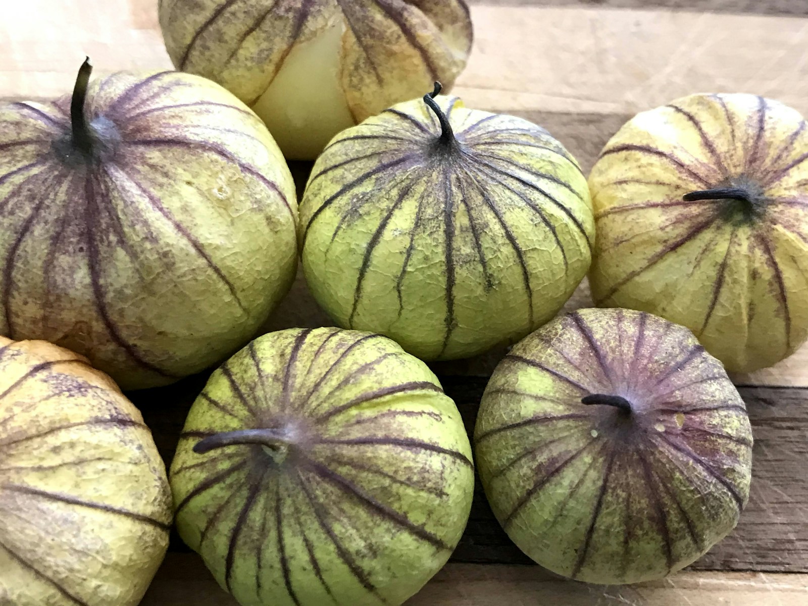 Freshly picked tomatillos with purple-veined husks on a wooden board