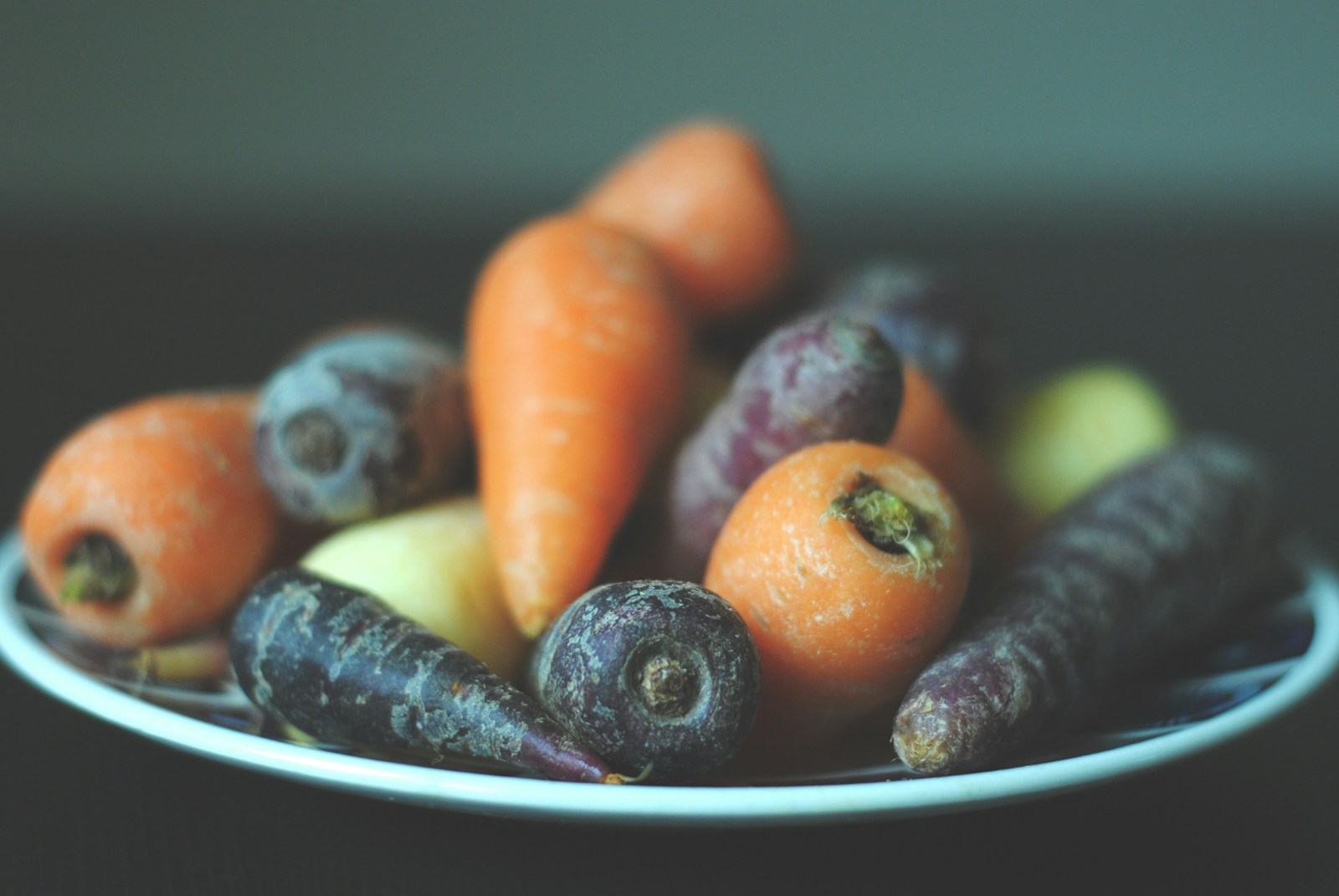 Purple, orange and pale yellow carrots piled on a plate