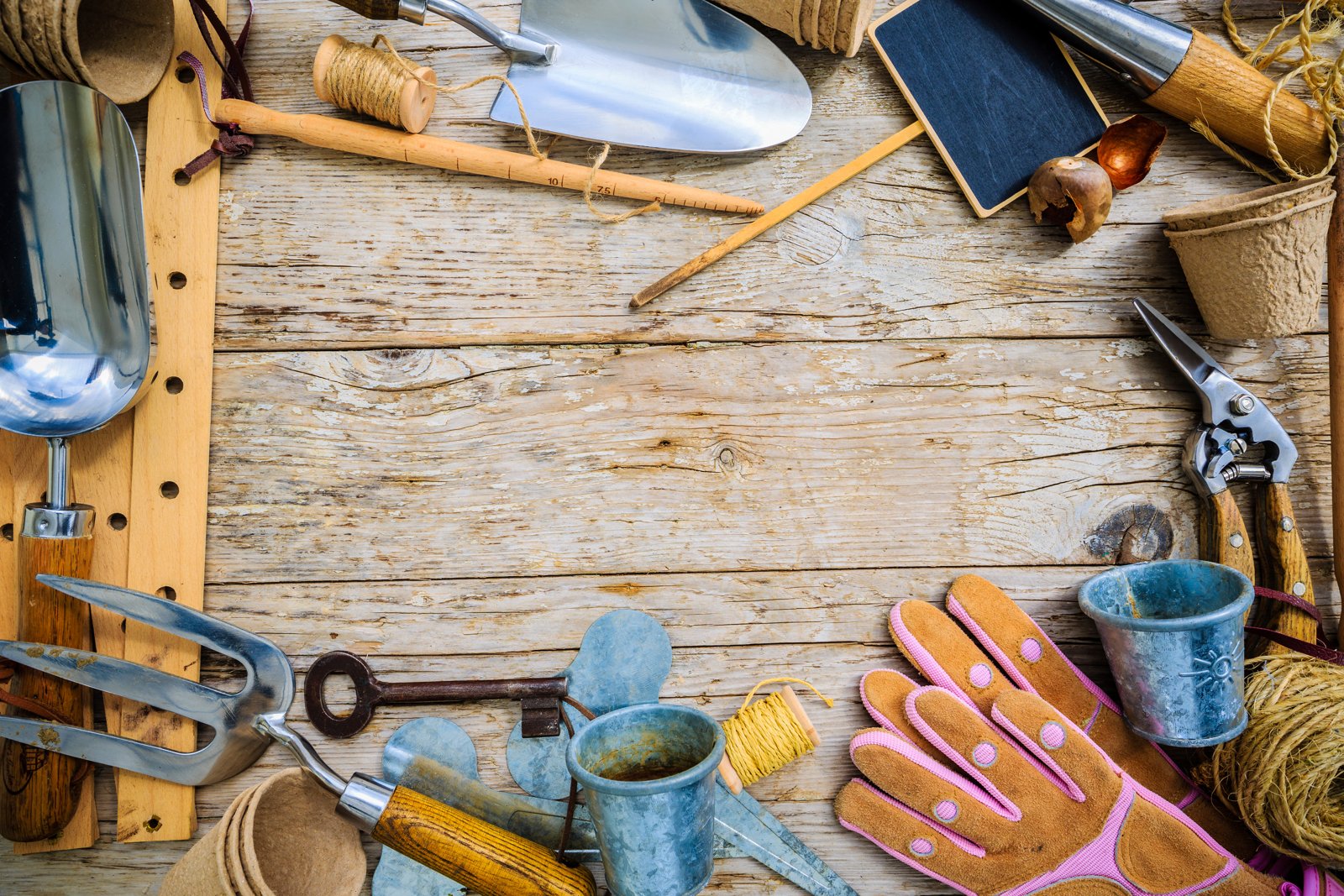 Hand fork, trowel, twine and gloves laid out on weathered boards