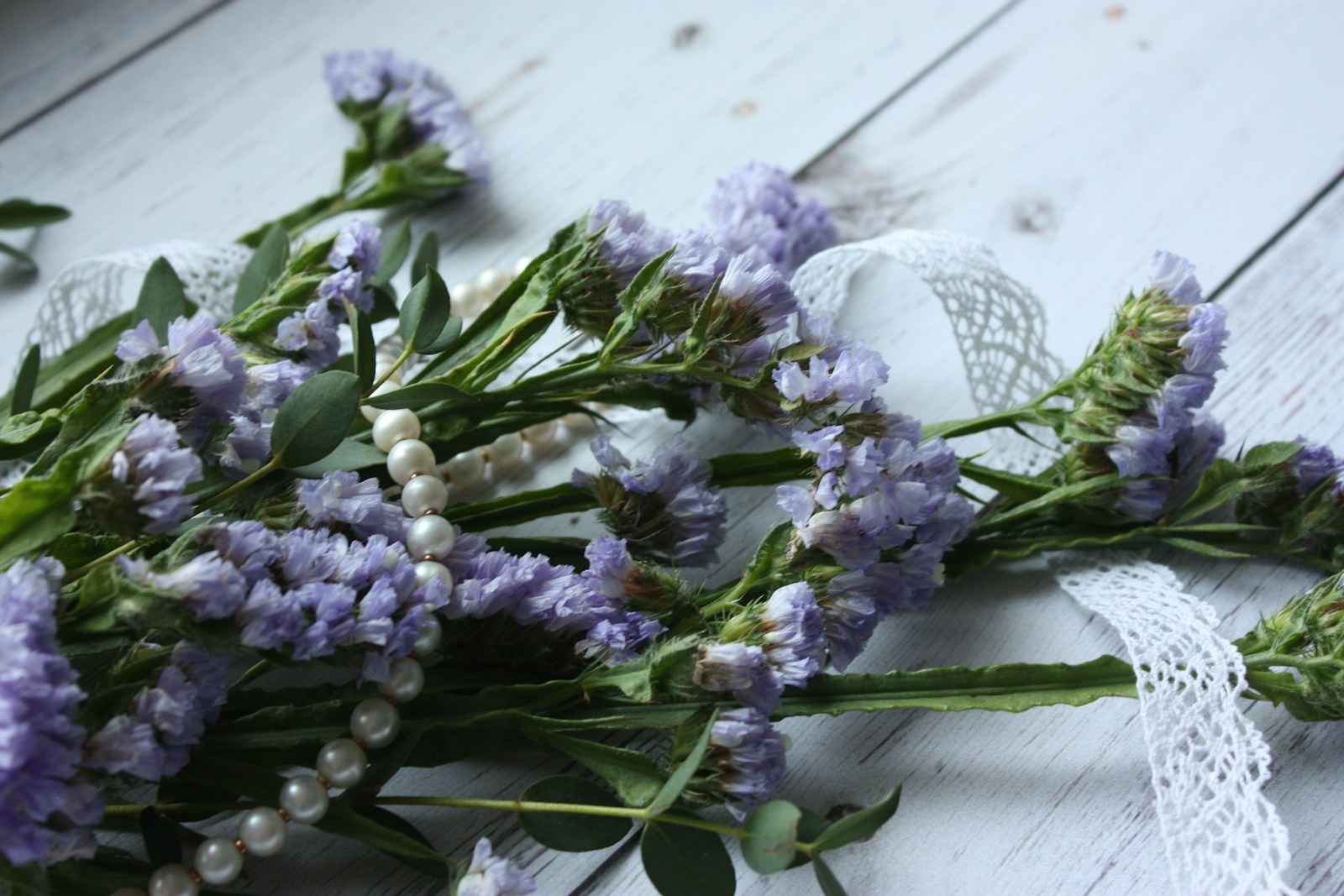 Freshly cut lavender-blue statice stems laid on a white wooden table