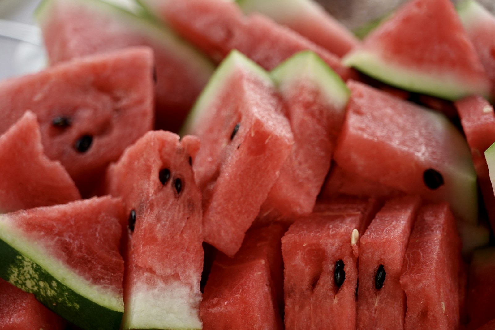 Pile of cut watermelon pieces with black seeds in red flesh